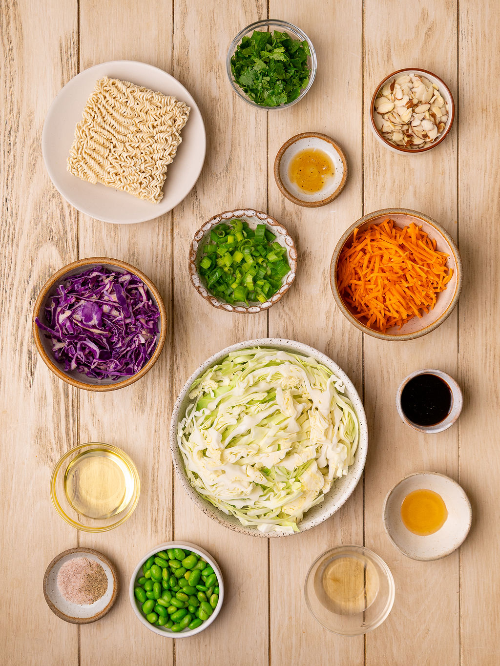 Ingredients for ramen noodle salad on a rustic wooden surface.