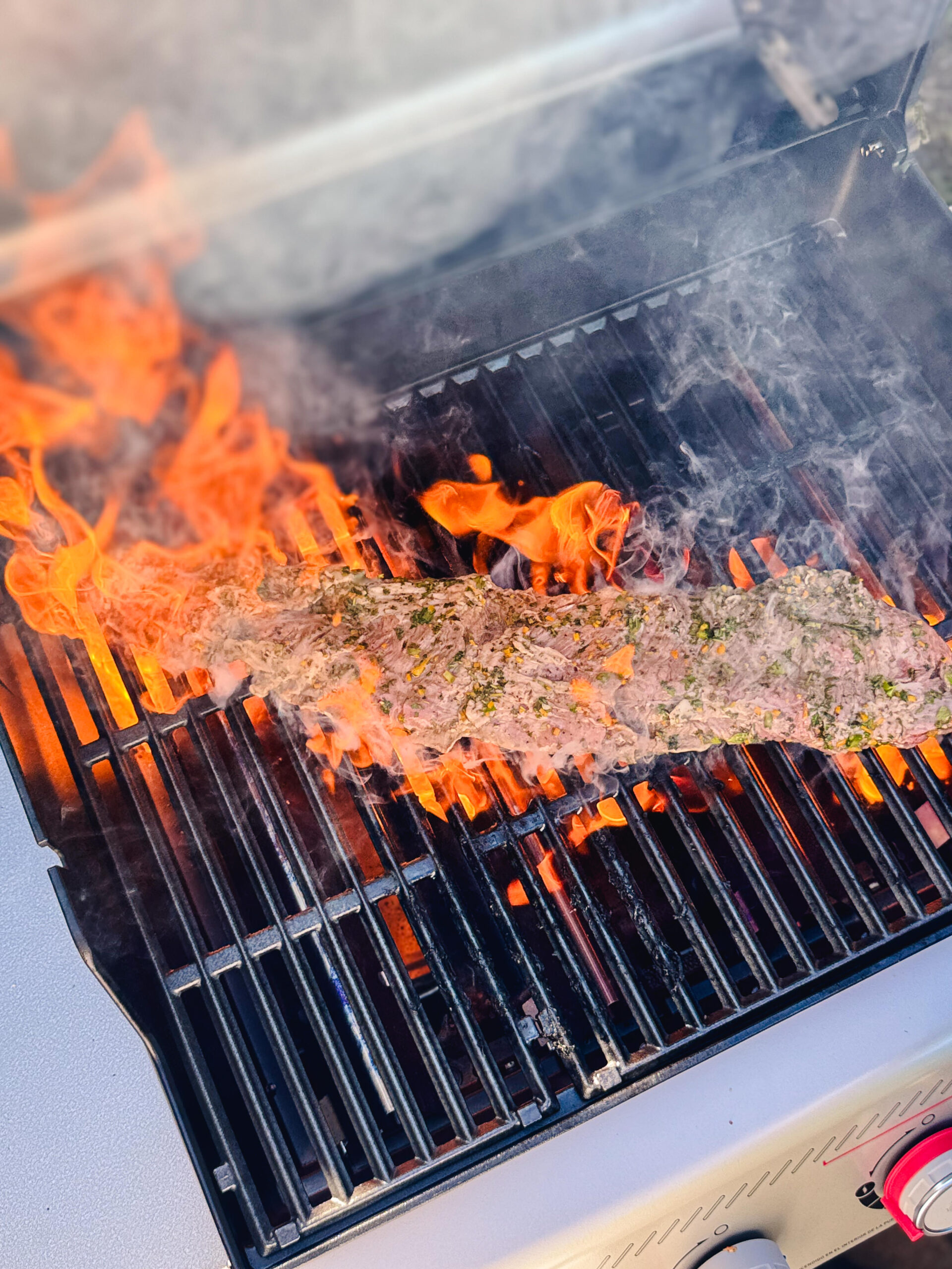 Skirt steak over an open flame on the grill.