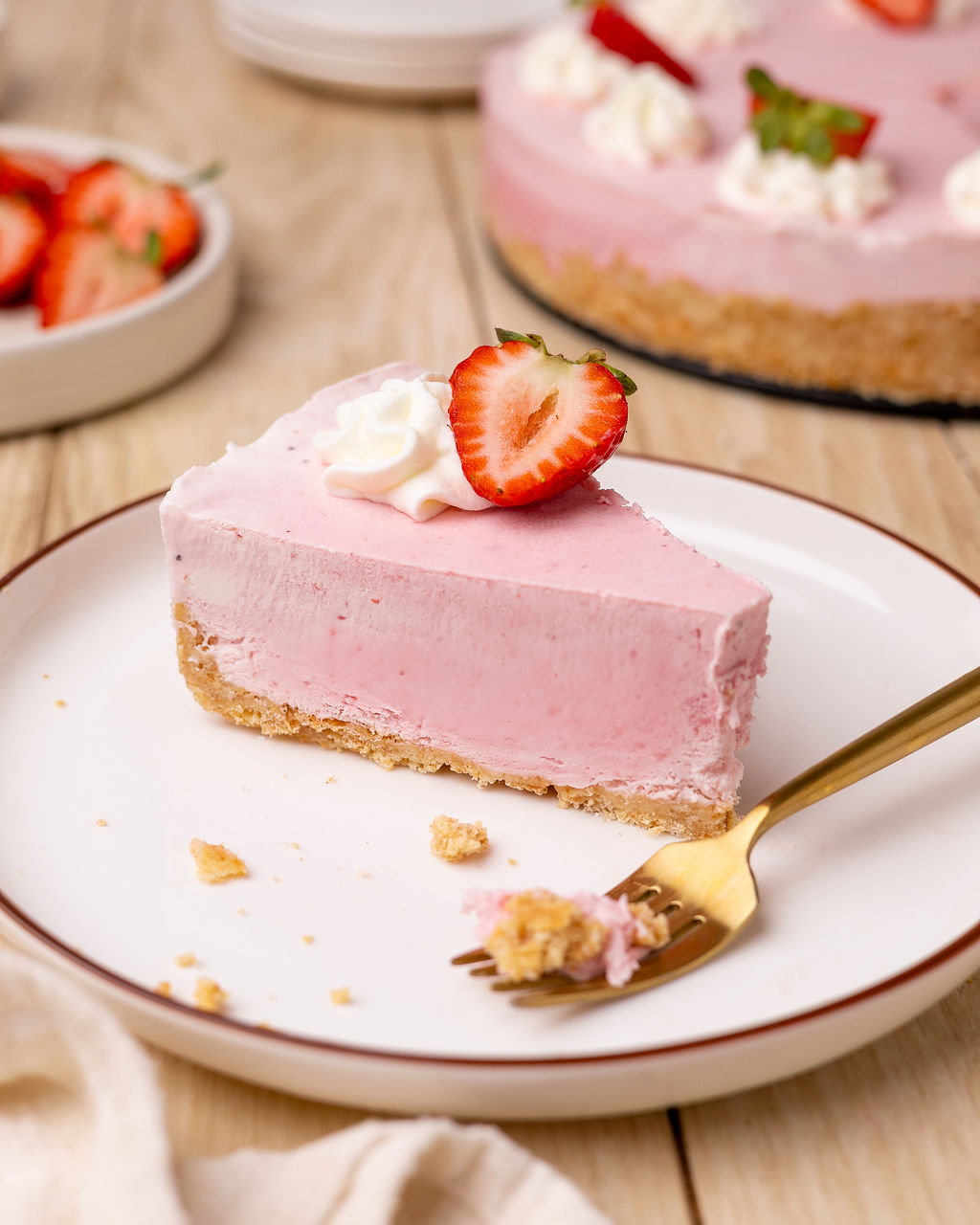 A slice of strawberry icebox pie with a fork garnished with a strawberry slice.