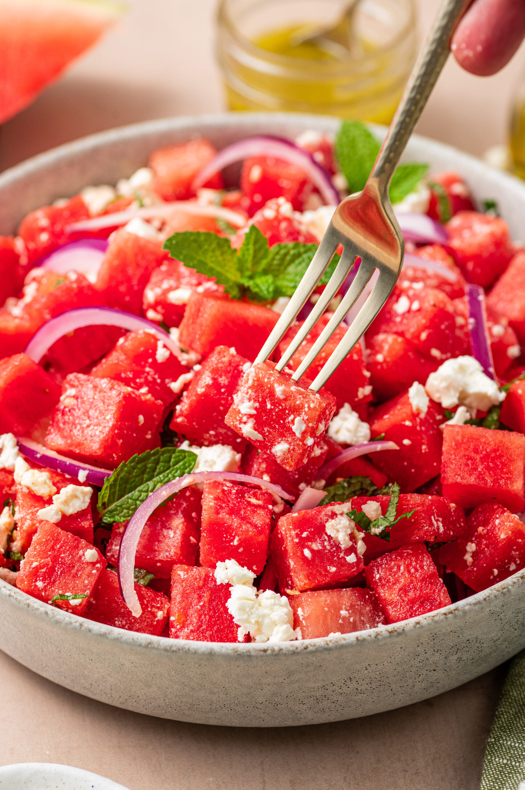 Dipping a fork into a bowl of watermelon feta salad.