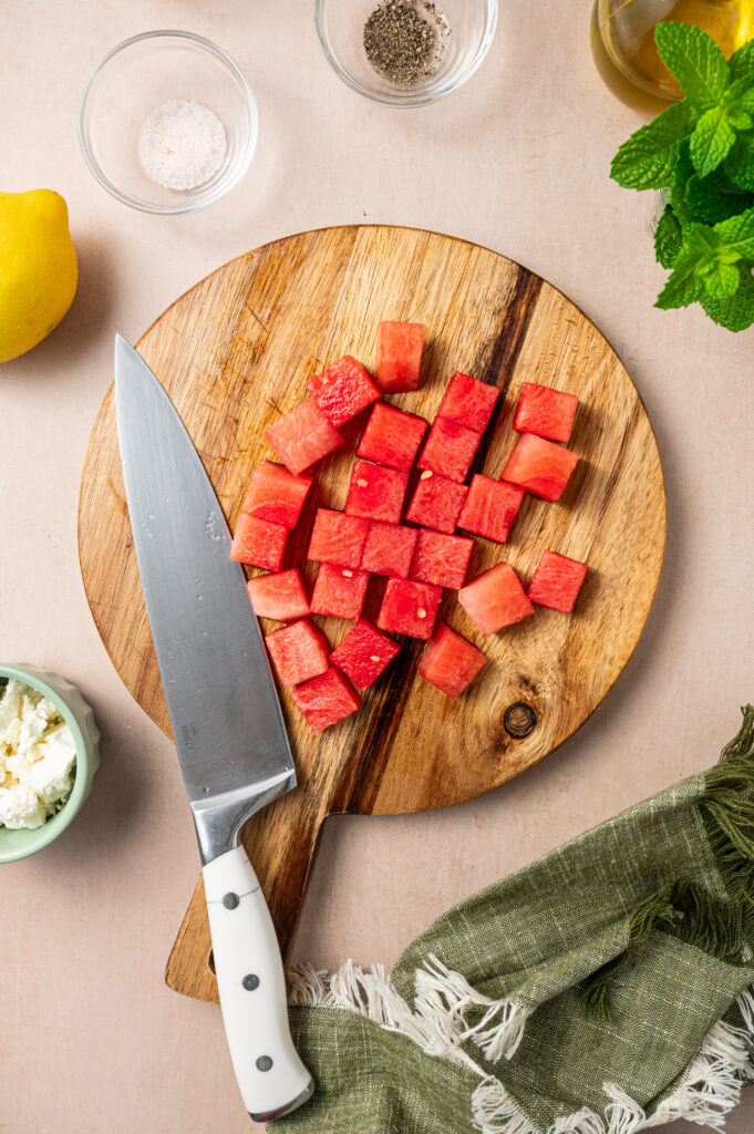 Fresh watermelon cut into cubes on a cutting board.