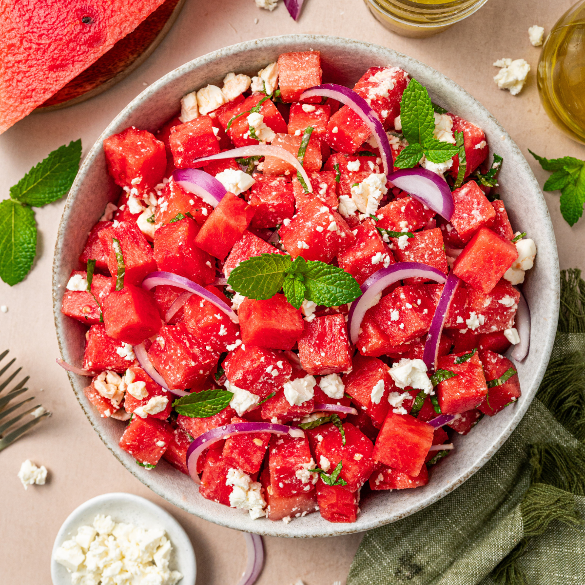 Watermelon feta salad with feta and mint surrounded by ingredients.