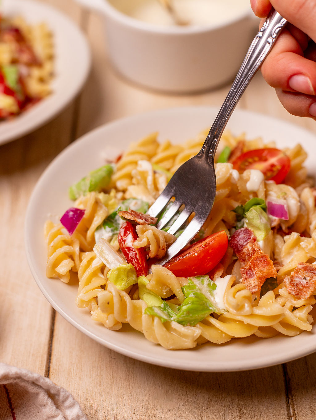 Dipping a fork into a BLT pasta salad.