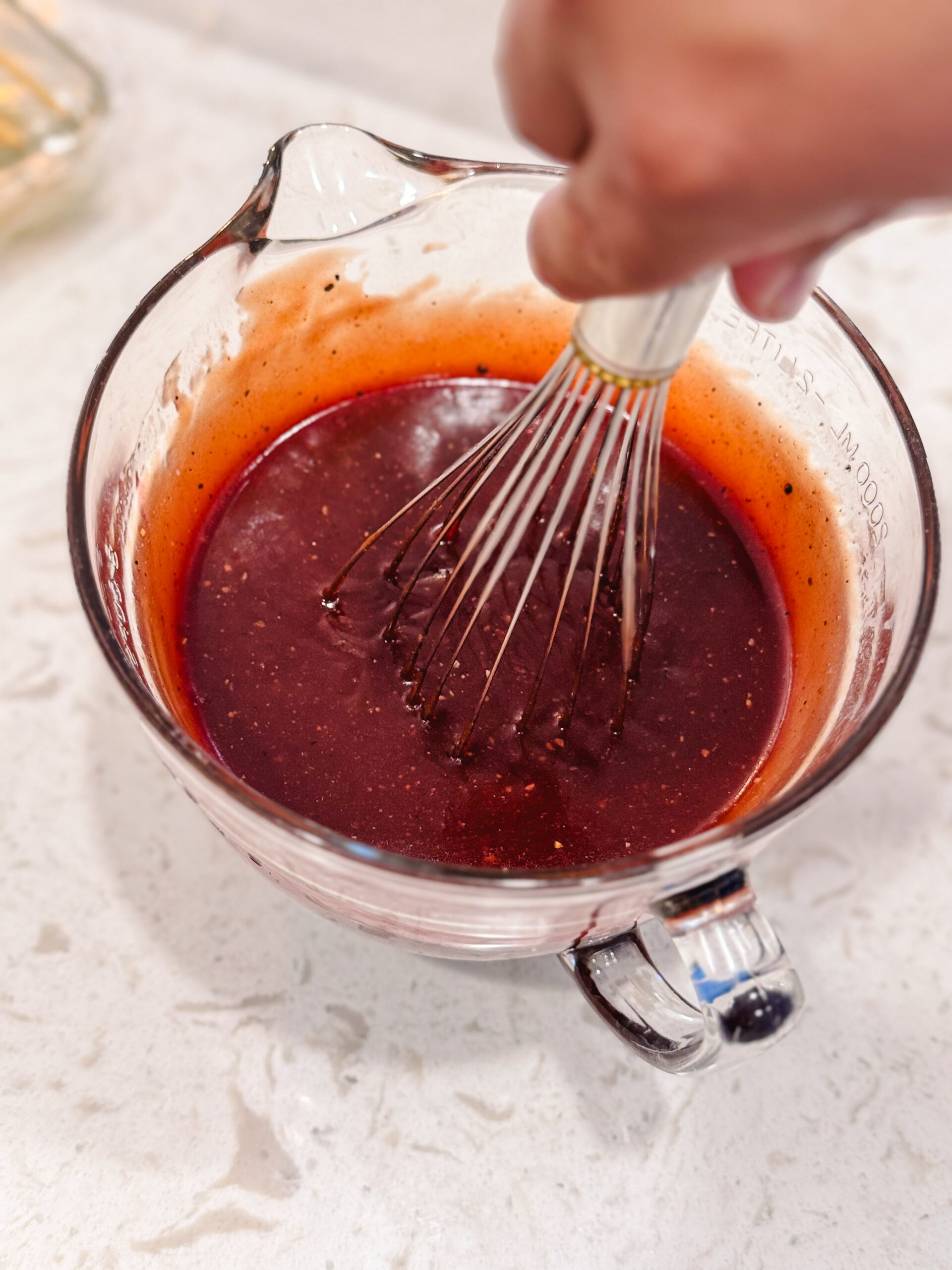 Whisking the barbecue sauce in a glass measuring cup.