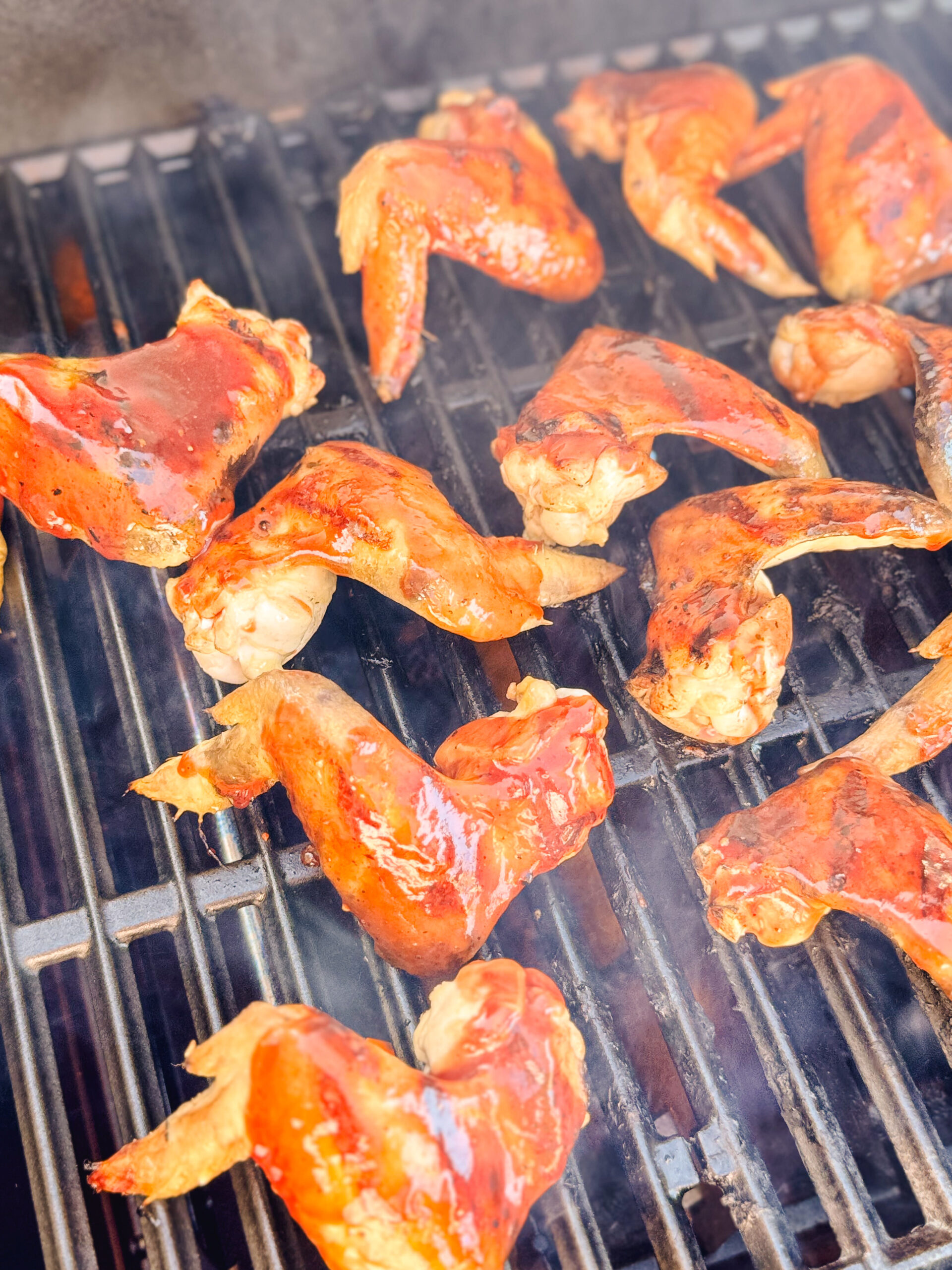 Chicken wings on a grill basted with BBQ sauce.