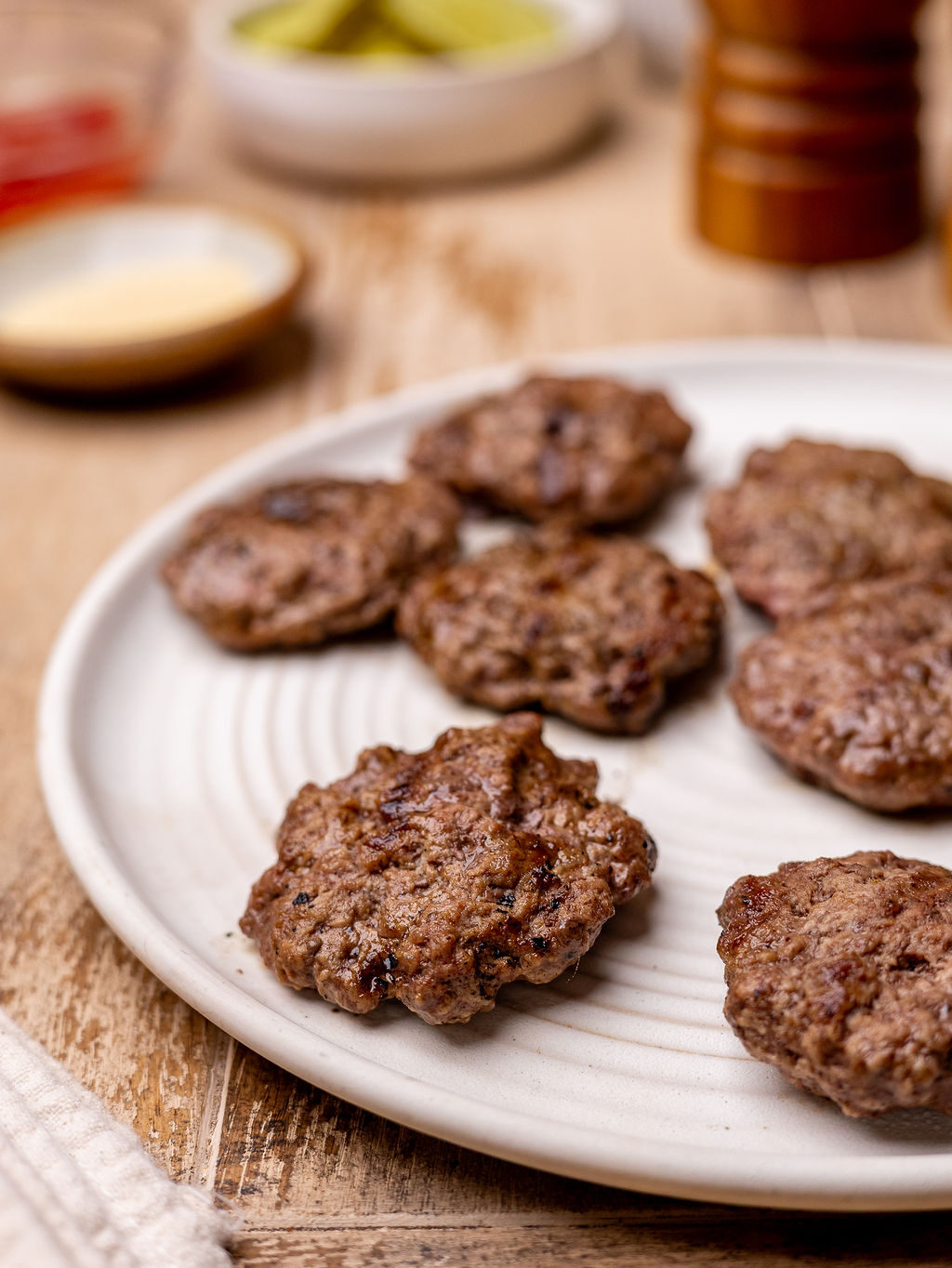 Burger patties fresh off the grill on a white plate.