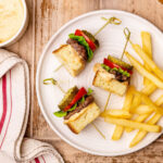A serving of grilled burger skewers on a white plate served with French fries.