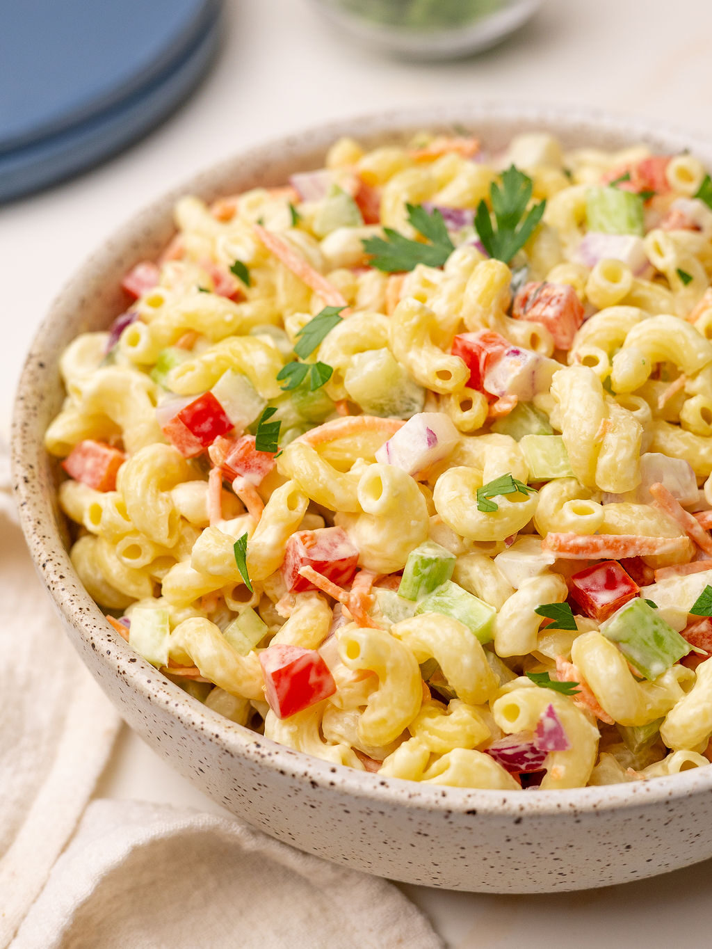Macaroni pasta salad in a serving bowl with garnish.