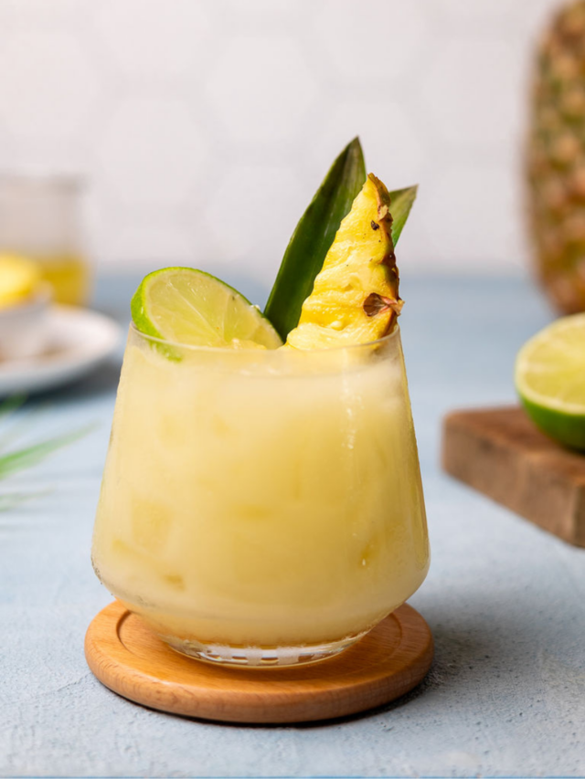 Pineapple coconut cooler in a glass with pineapple and lime as a garnish.