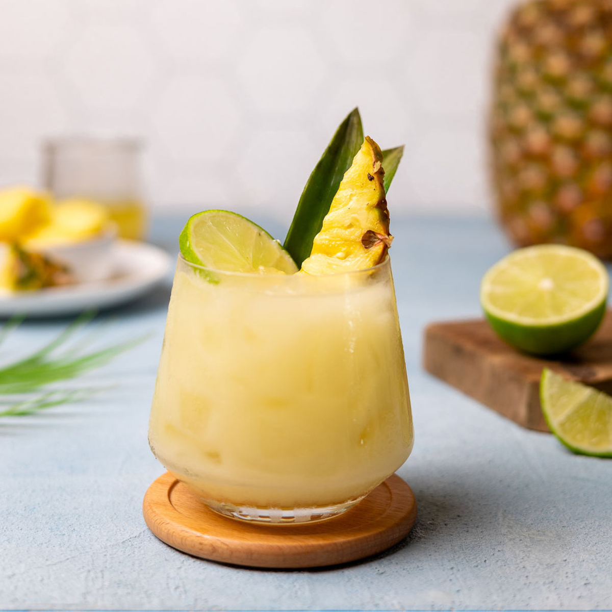 Pineapple coconut cooler in a glass with pineapple and lime as a garnish.
