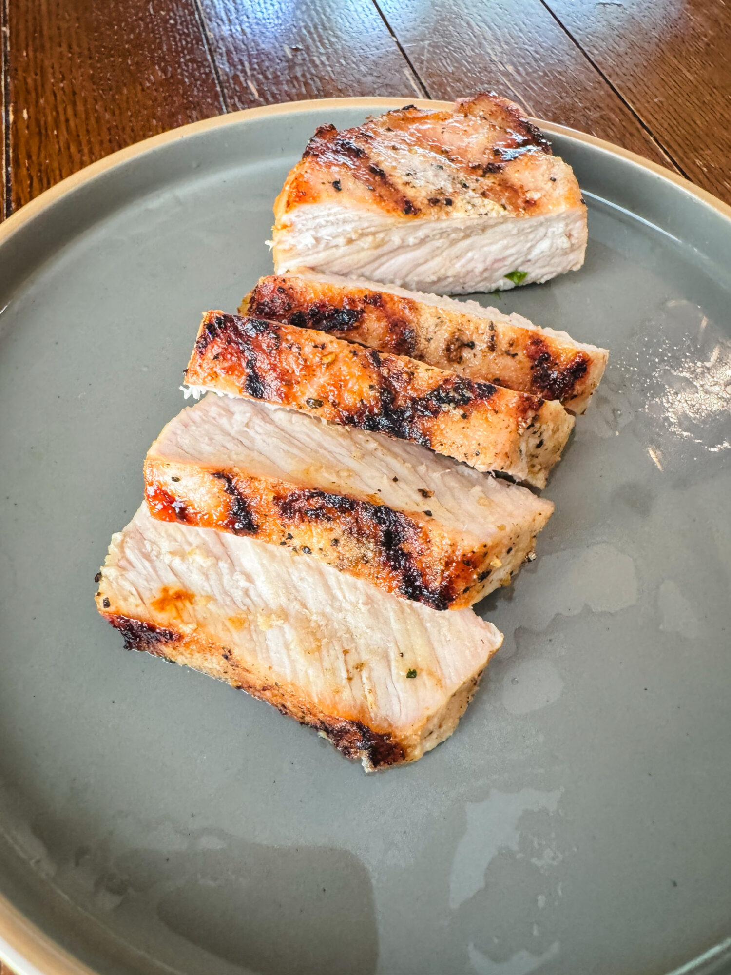 Sliced lemon Dijon grilled pork chops on a gray plate.