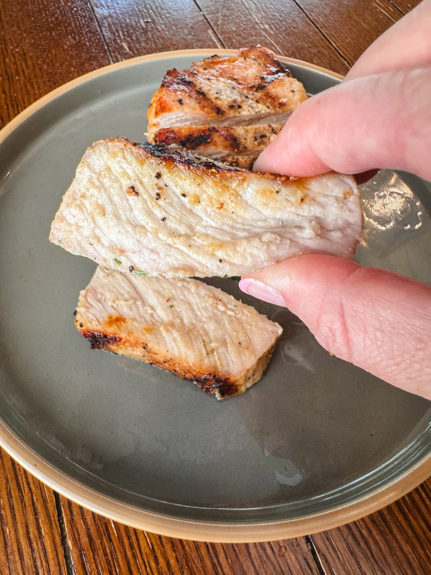 A juicy slice of lemon Dijon grilled pork chops squeezed between two fingers.