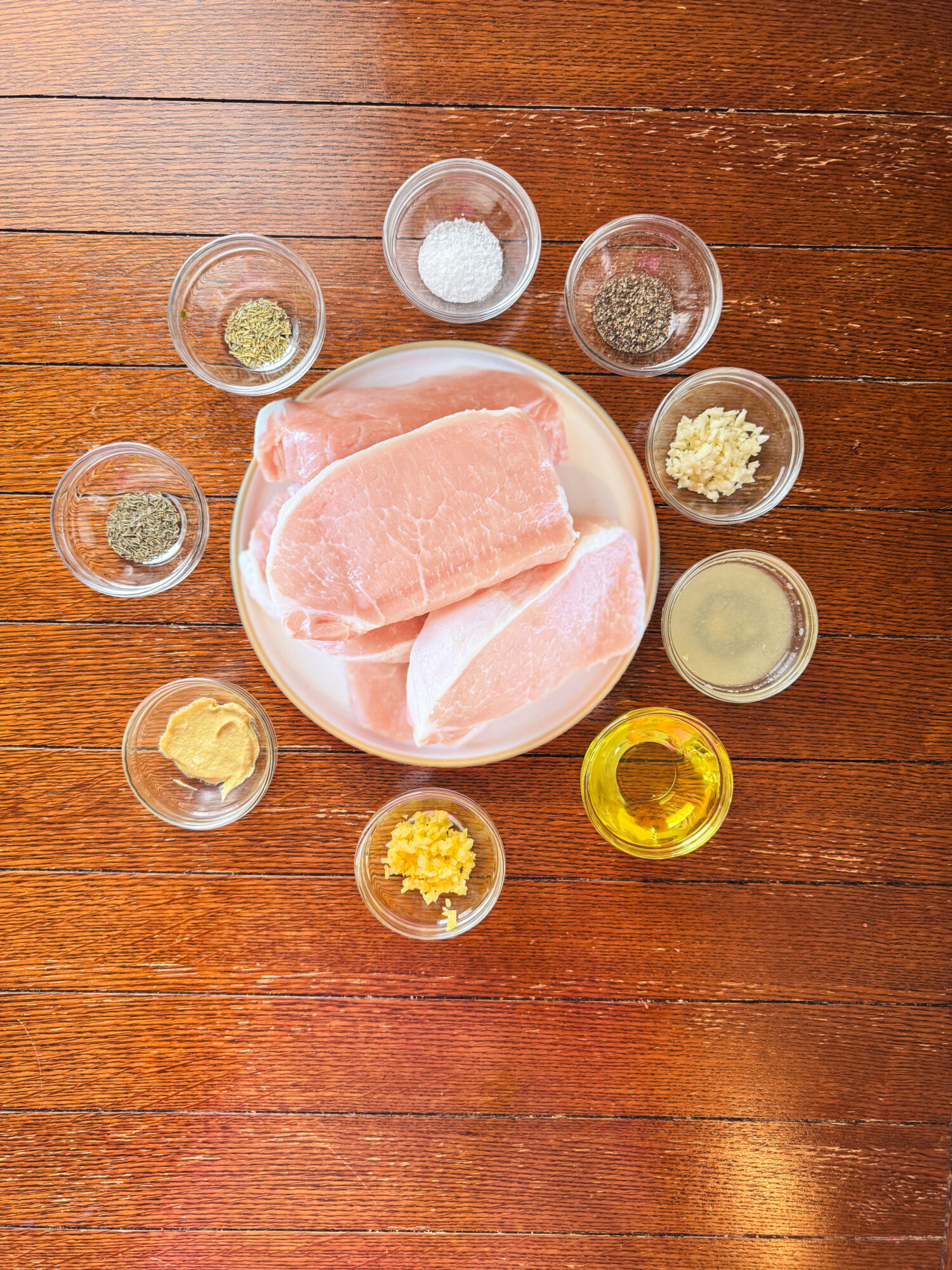 Ingredients for lemon Dijon grilled pork chops over a wooden table.