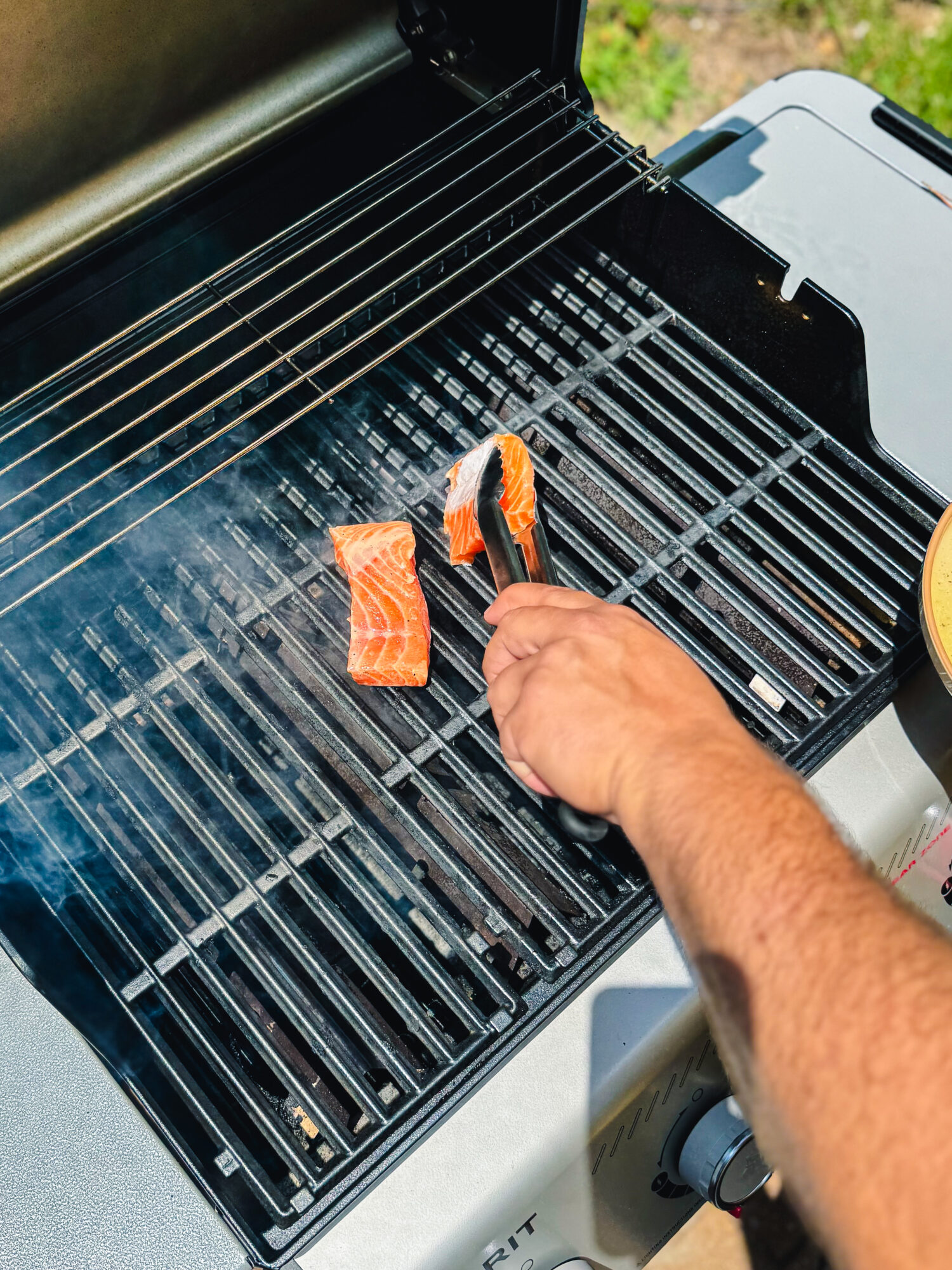 Adding salmon to a grill.