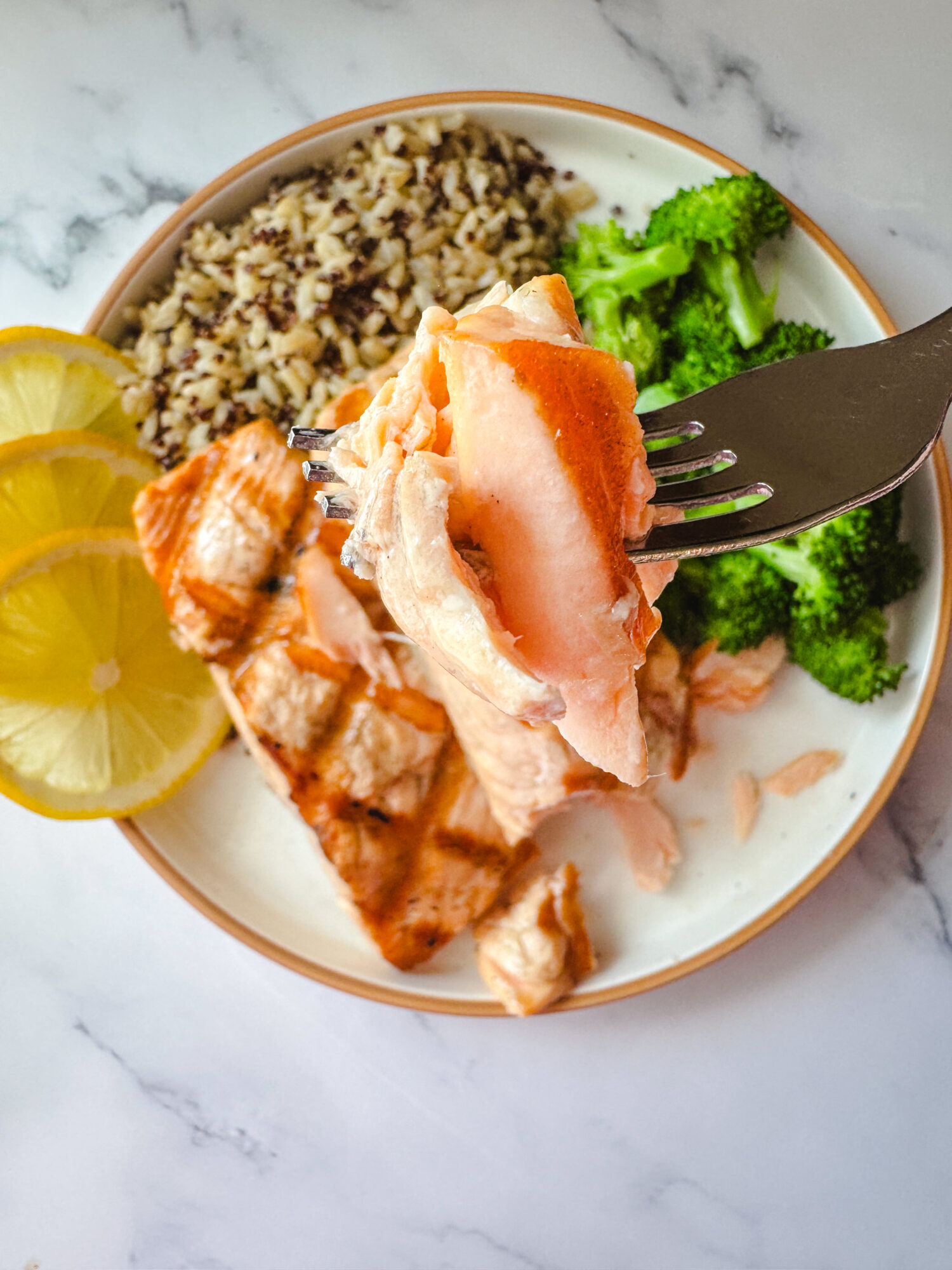 A forkful of grilled salmon over a plate.