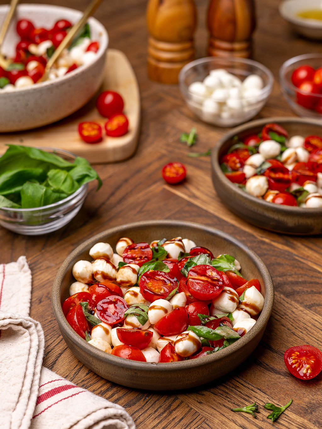 Caprese salad in a white bowl surrounded by ingredients.