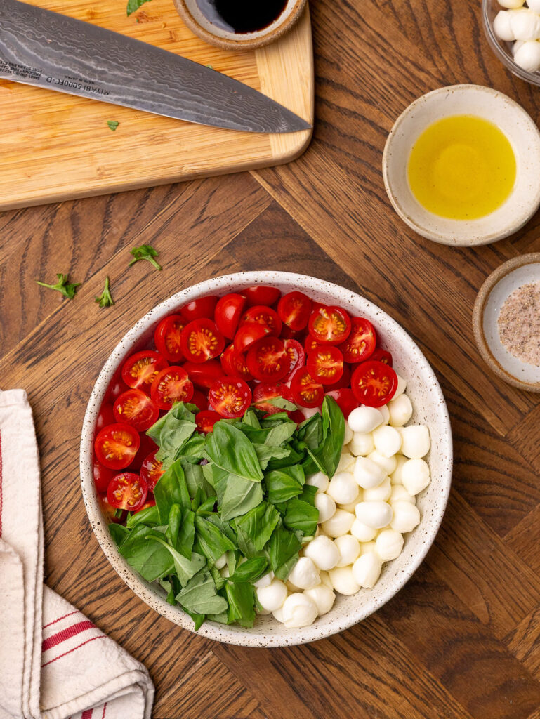 Ingredients for caprese salad in a bowl before getting tossed.