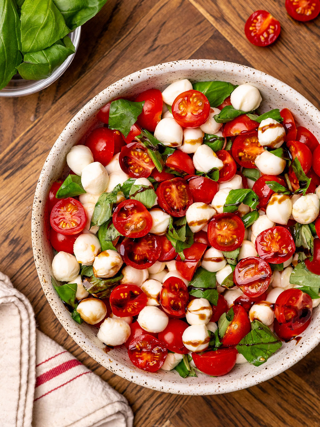 Aerial view of tossed caprese salad in a white bowl.