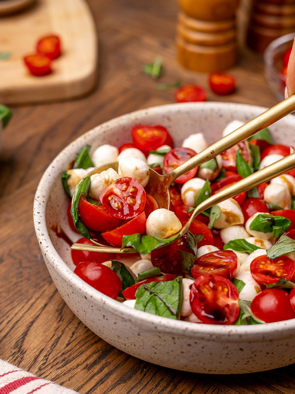 Salad thongs in a bowl of caprese salad.