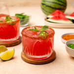 Watermelon tajin mocktail in a glass with a prig of mint as garnish.