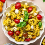 Pesto Tortellini Salad in a serving bowl garnished with basil.
