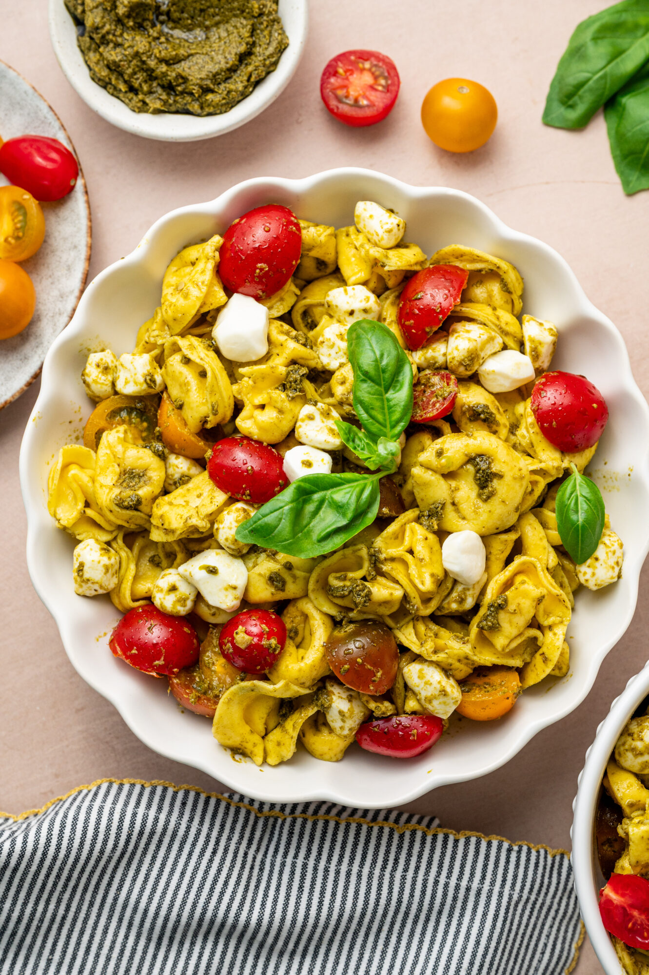 Pesto Tortellini Salad in a serving bowl garnished with basil.