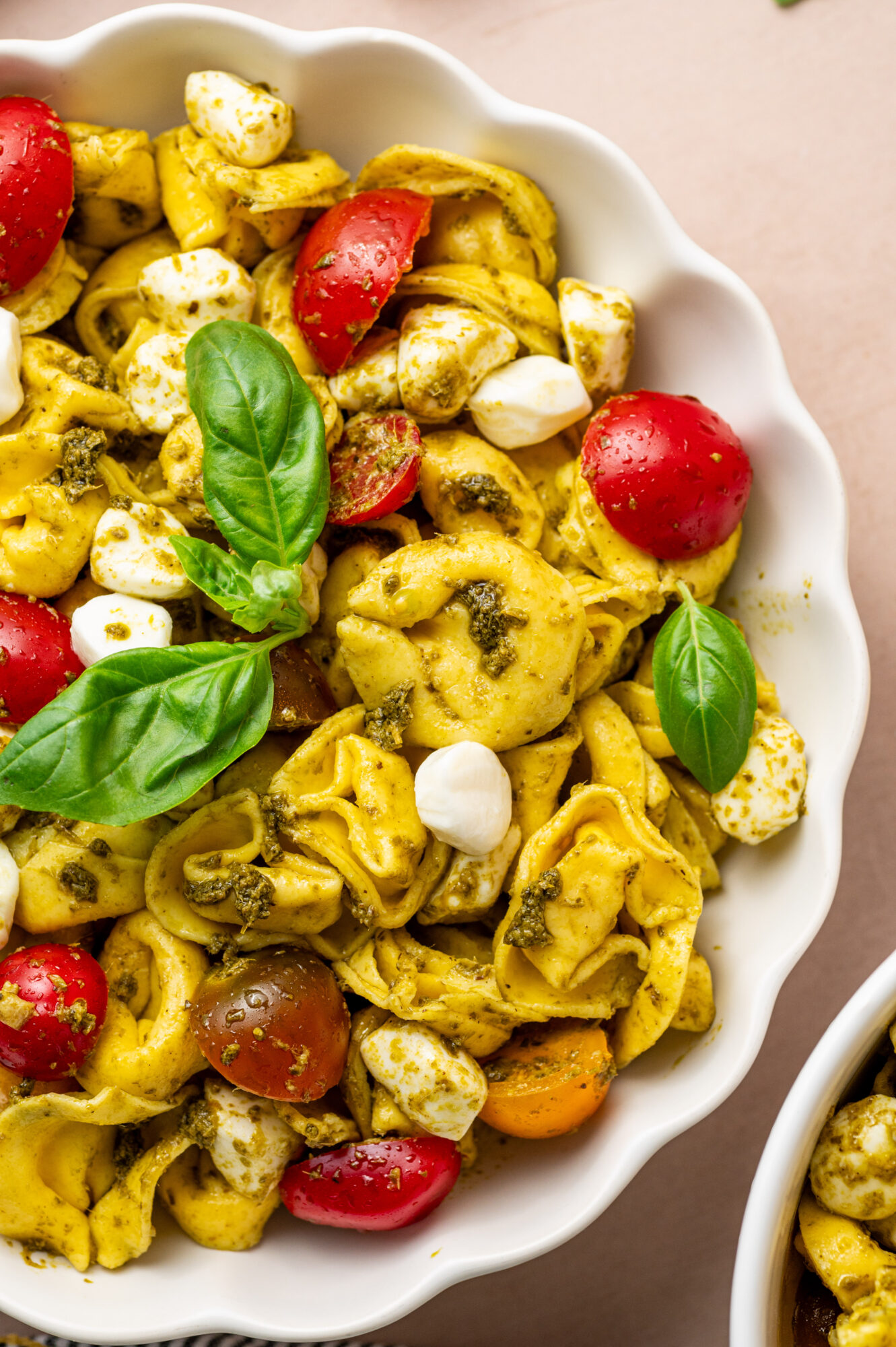 A white bowl of pesto tortellini salad.