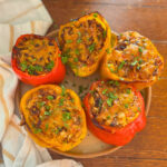 Air fryer stuffed peppers on a plate over a wooden surface.