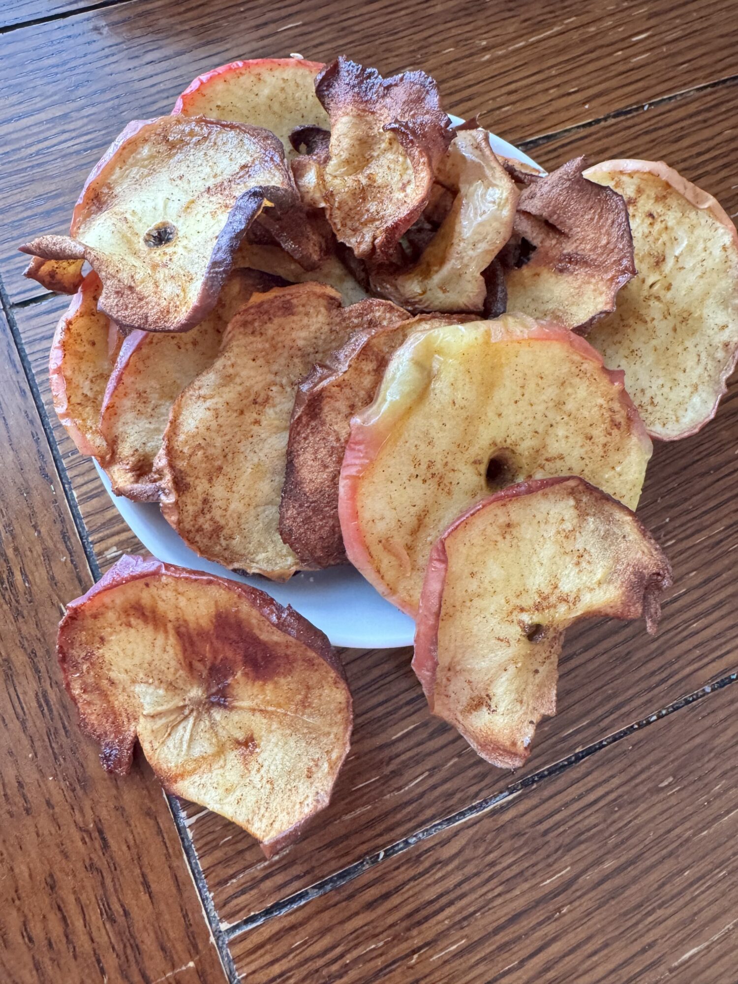 Air fryer apple chips in a bowl on a wooden table.