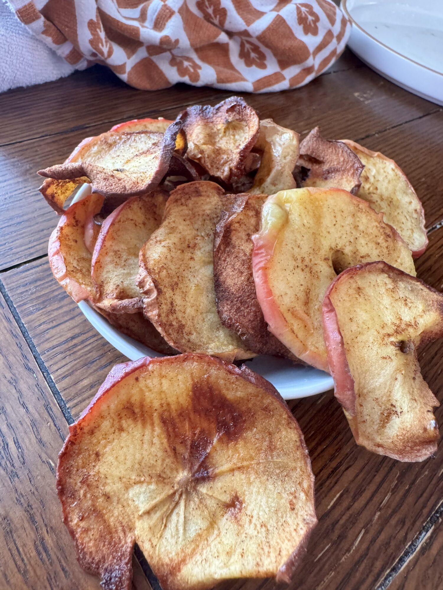 Air fryer apple chips in a bowl on a wooden table.