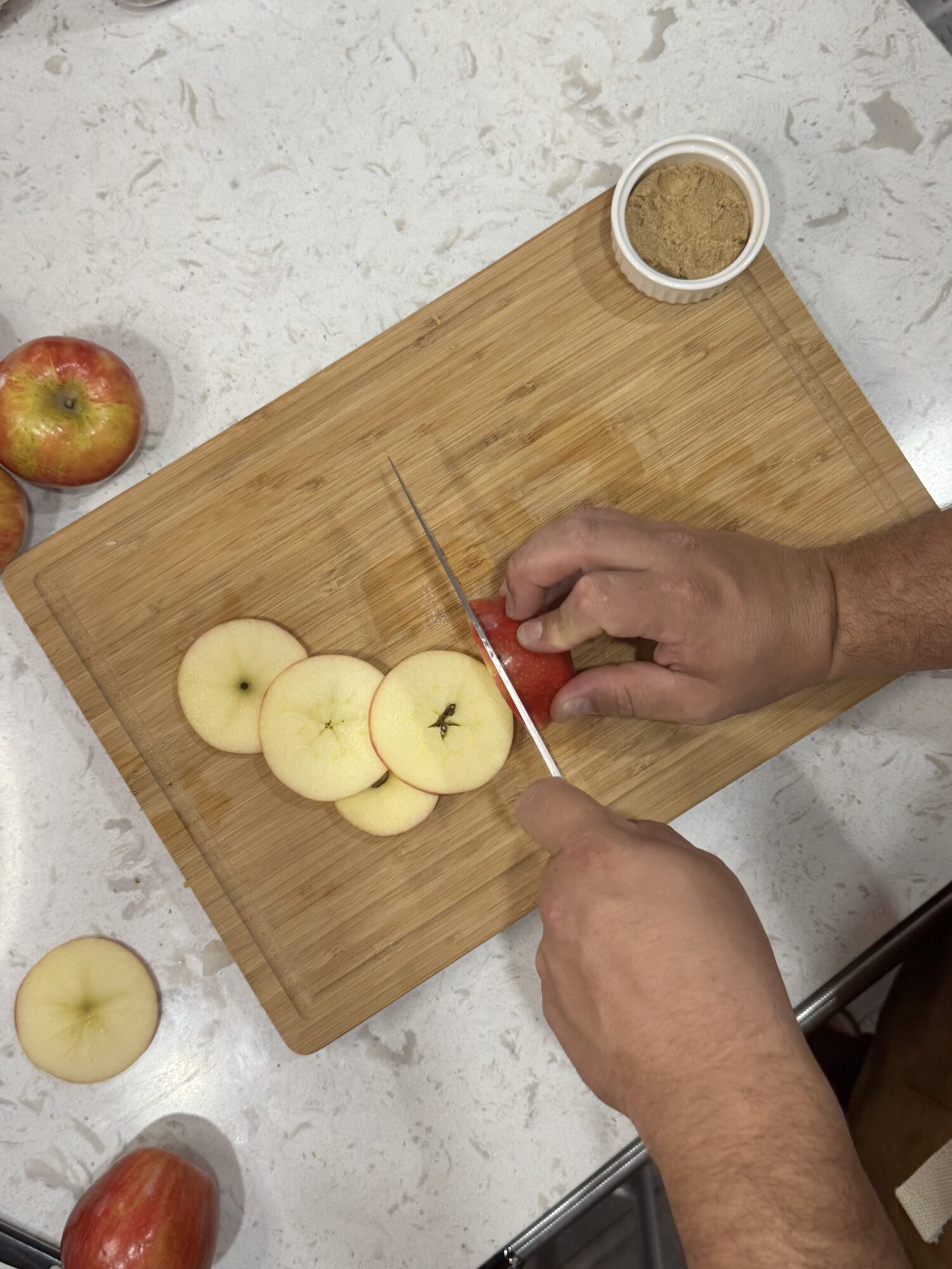 Slicing apples into rounds over a wooden cutting board.