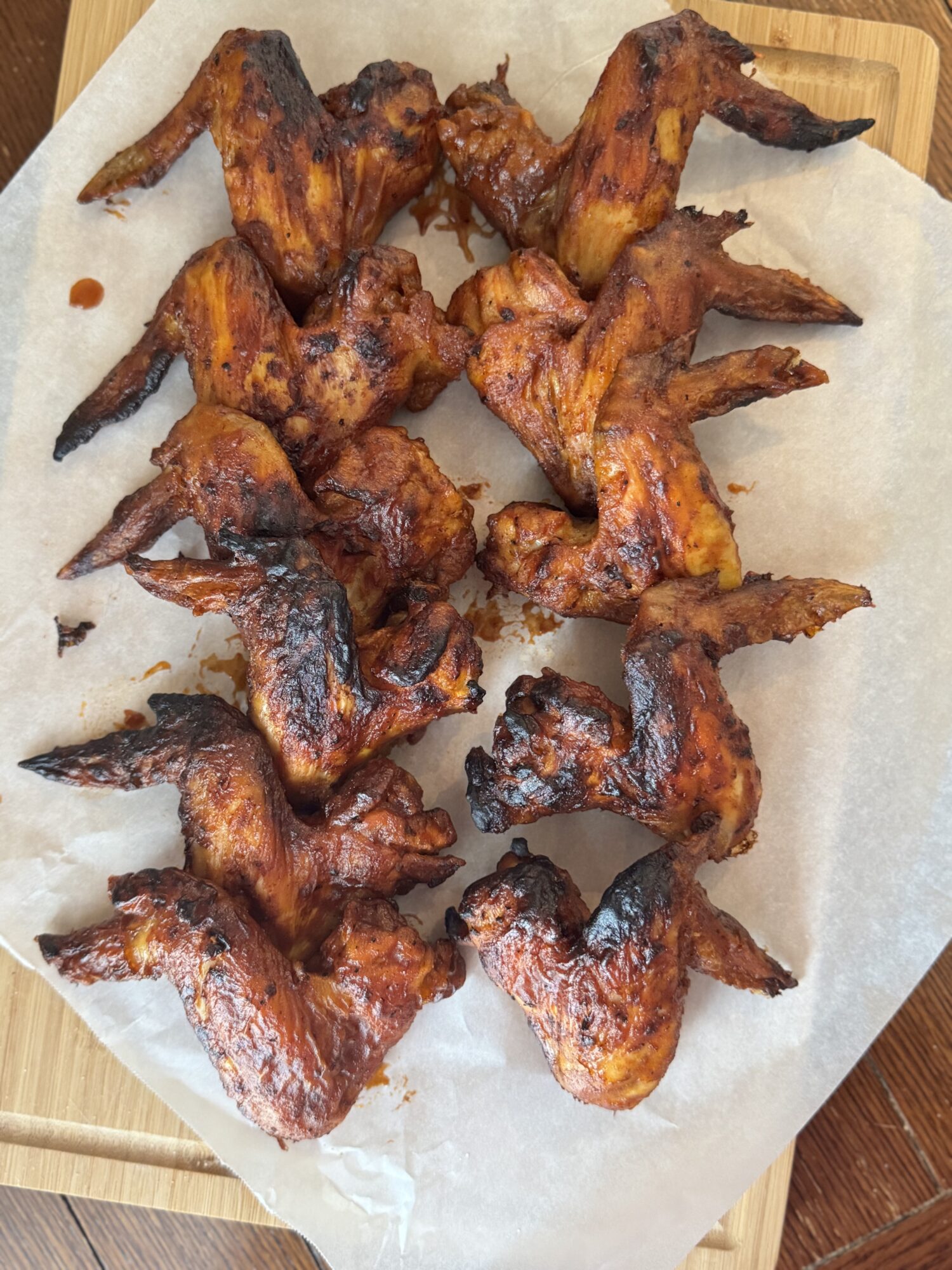 Two rows of air fryer BBQ chicken wings over parchment paper.