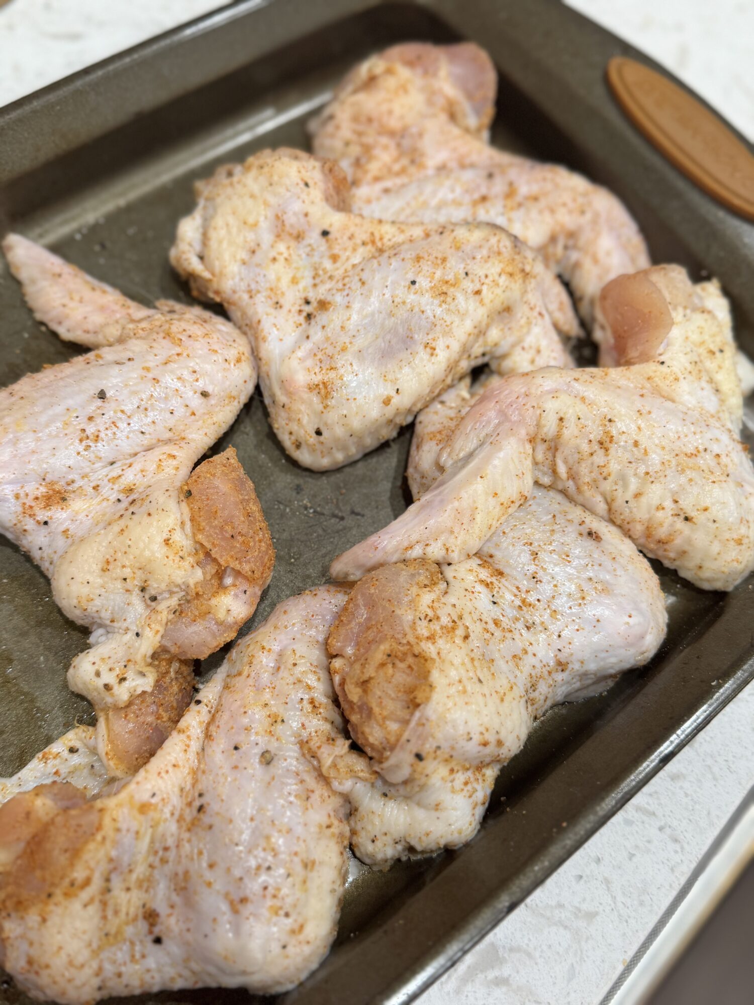 Seasoned raw chicken wings in a baking dish.