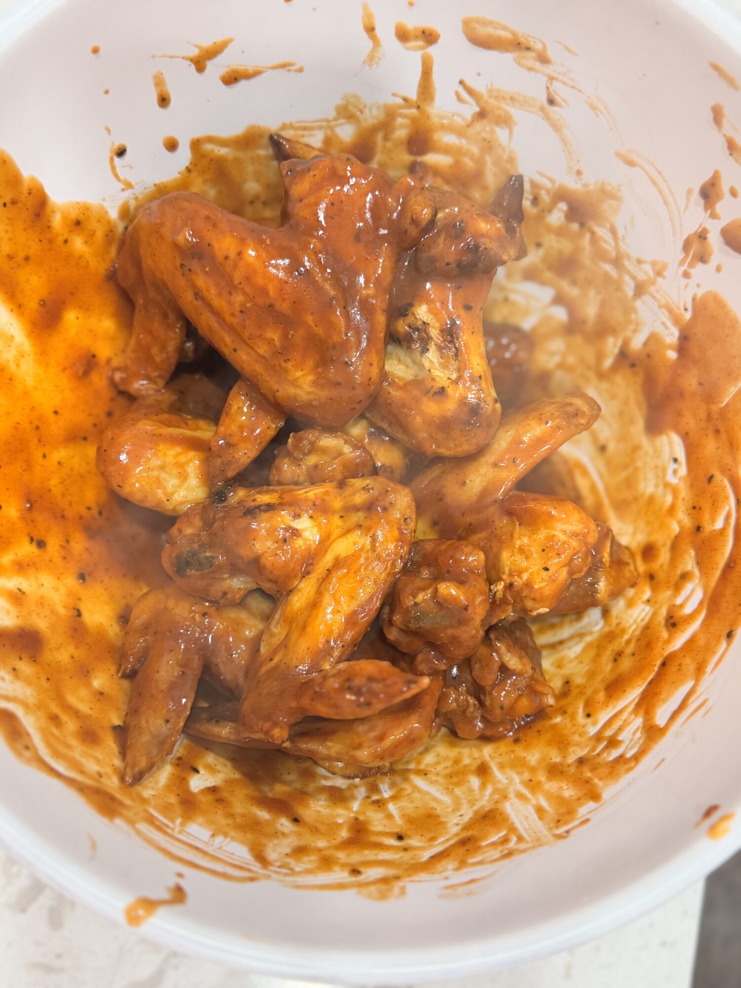 Chicken wings seasoned in a white bowl.