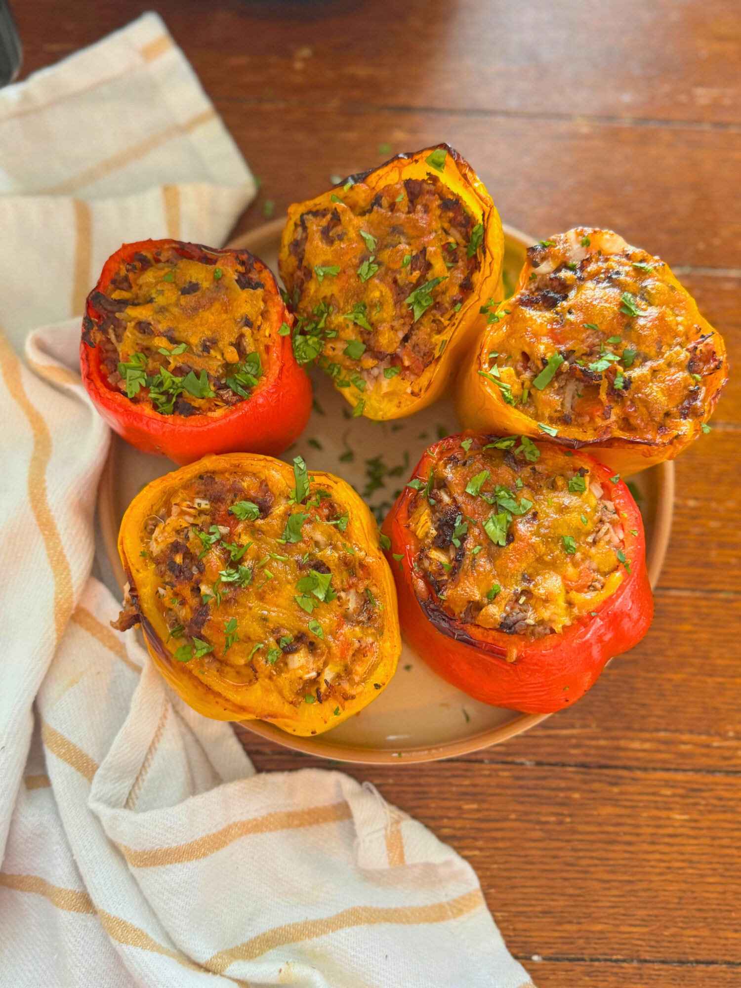 Air fryer stuffed peppers on a plate over a wooden surface.