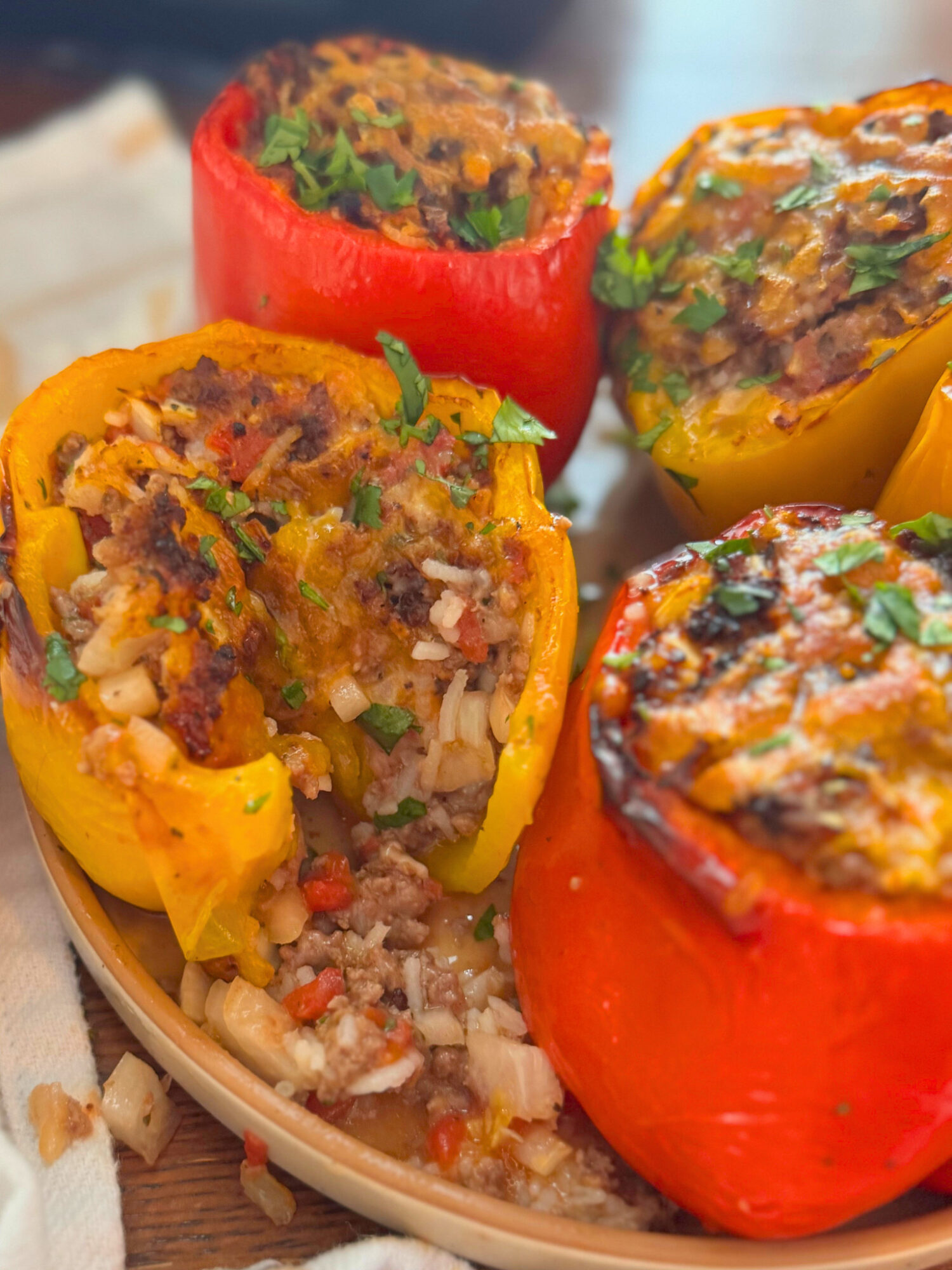 Air fryer stuffed peppers on a plate, with one stuffed pepper with a bite taken out.