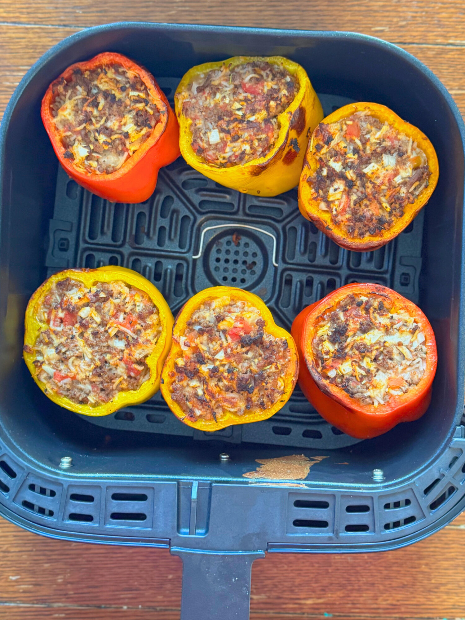 Stuffed peppers in an air fryer basket ready to eat.
