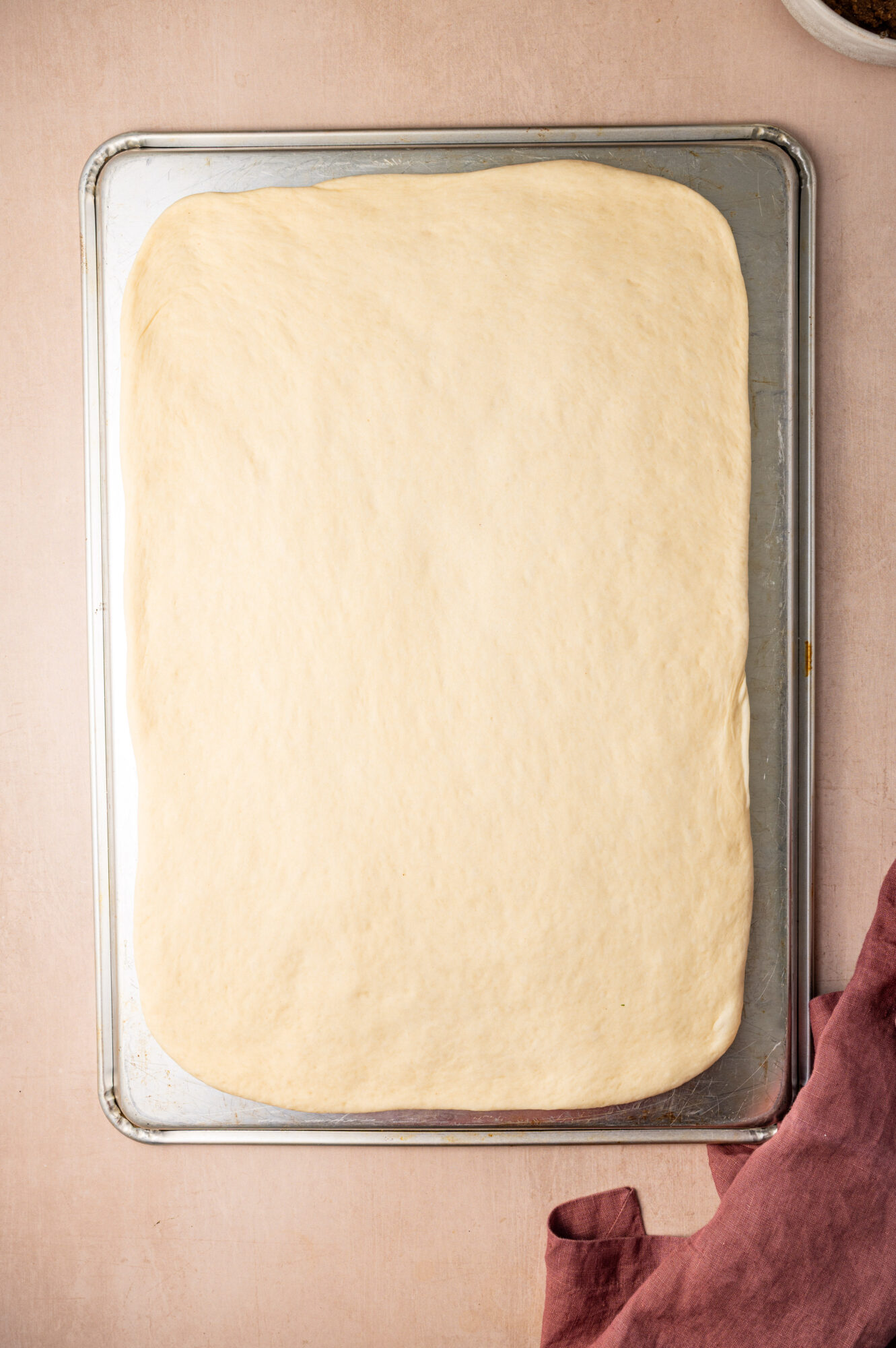 Cinnamon roll dough rolled out on a pan.