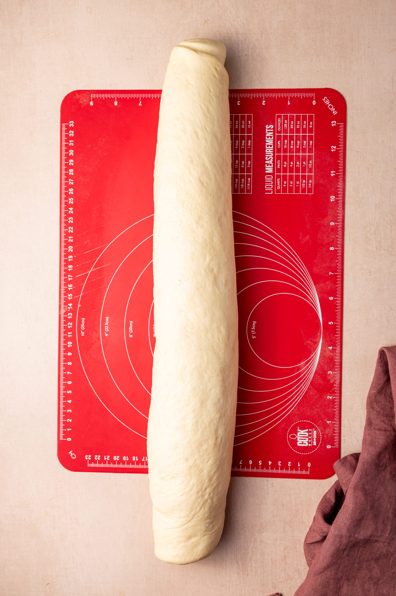 A cinnamon roll log on a red cutting board.