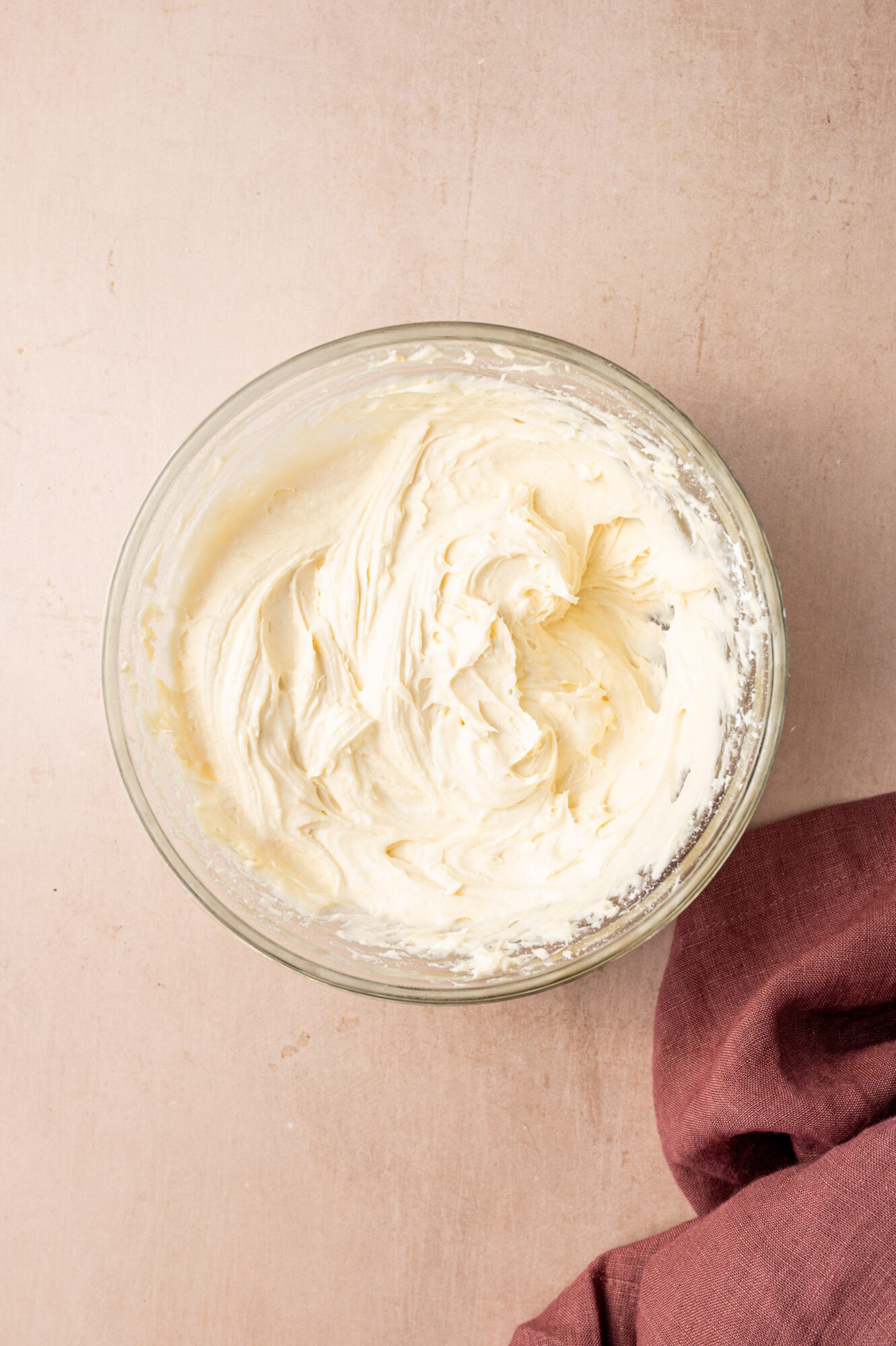 Cream cheese frosting in a glass bowl.
