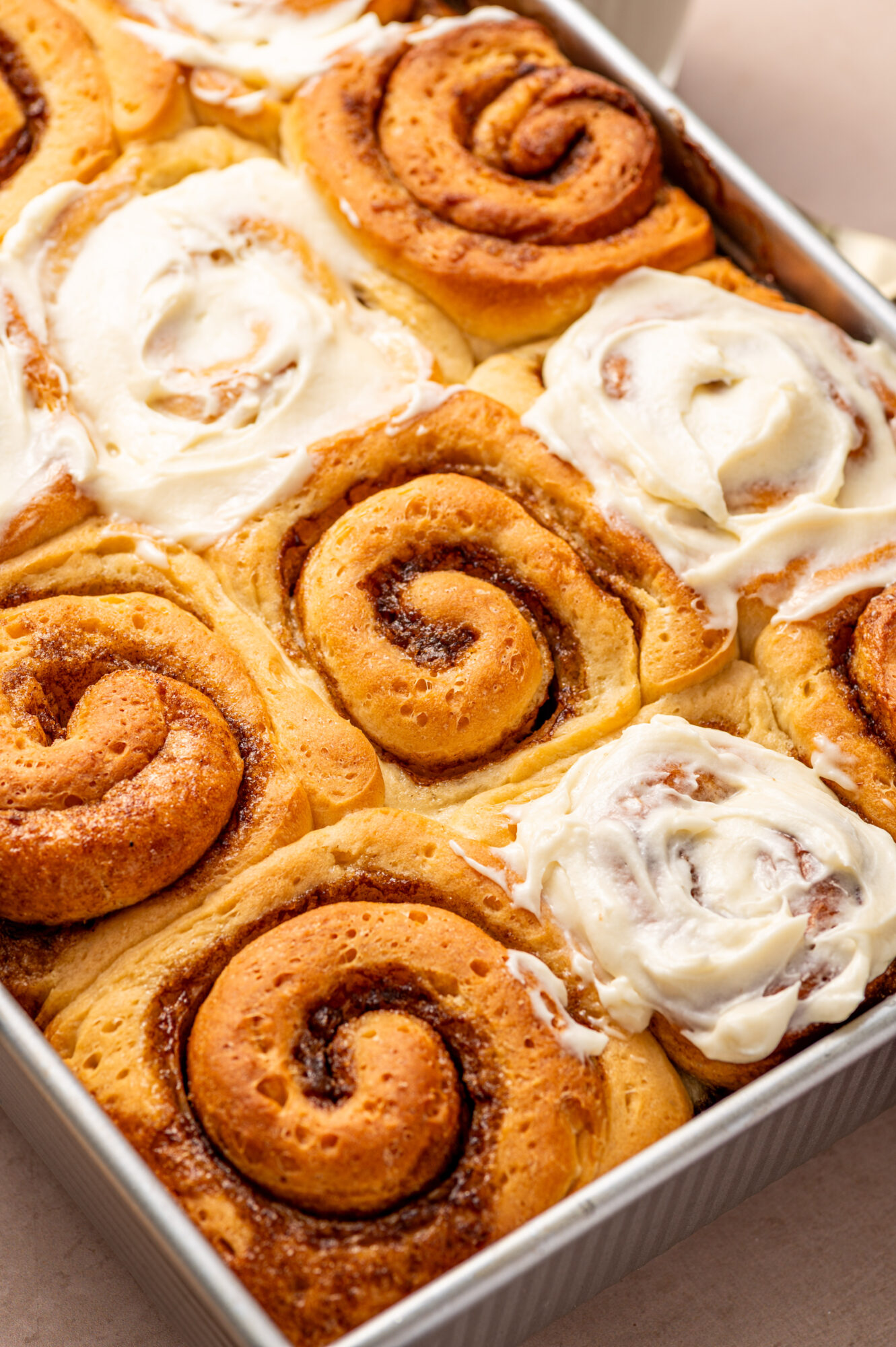 Cinnamon rolls in a baking dish, some frosted and some not.