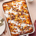Cinnamon roll casserole drizzled with icing in a baking dish.