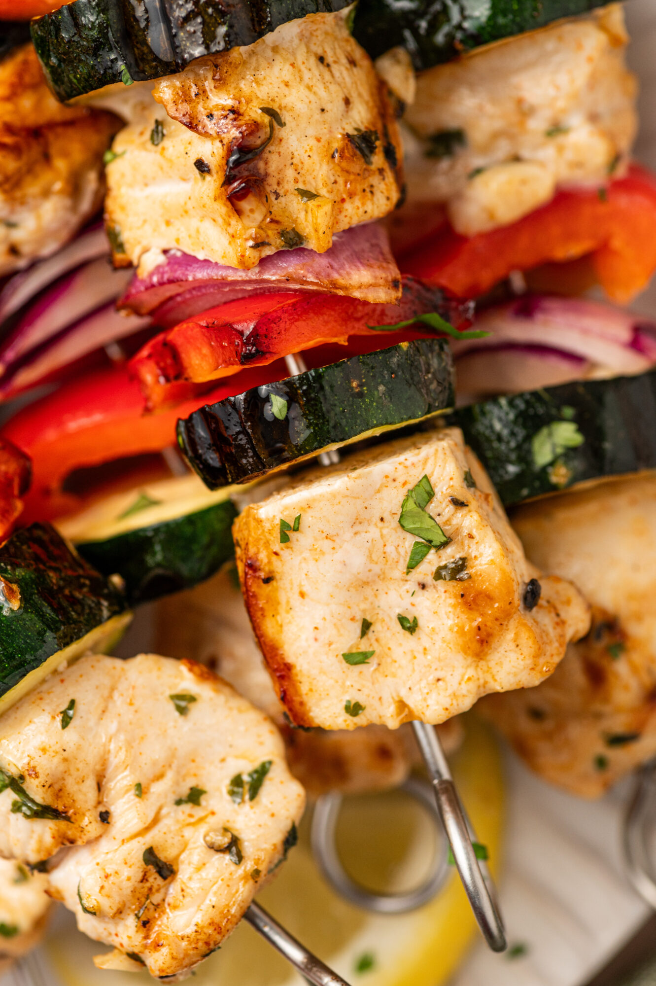 Close-up of grilled chicken kabobs with red onion, bell pepper, and zucchini.