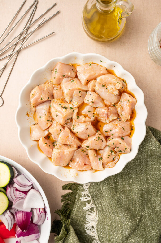 Raw chicken marinating in a white bowl.