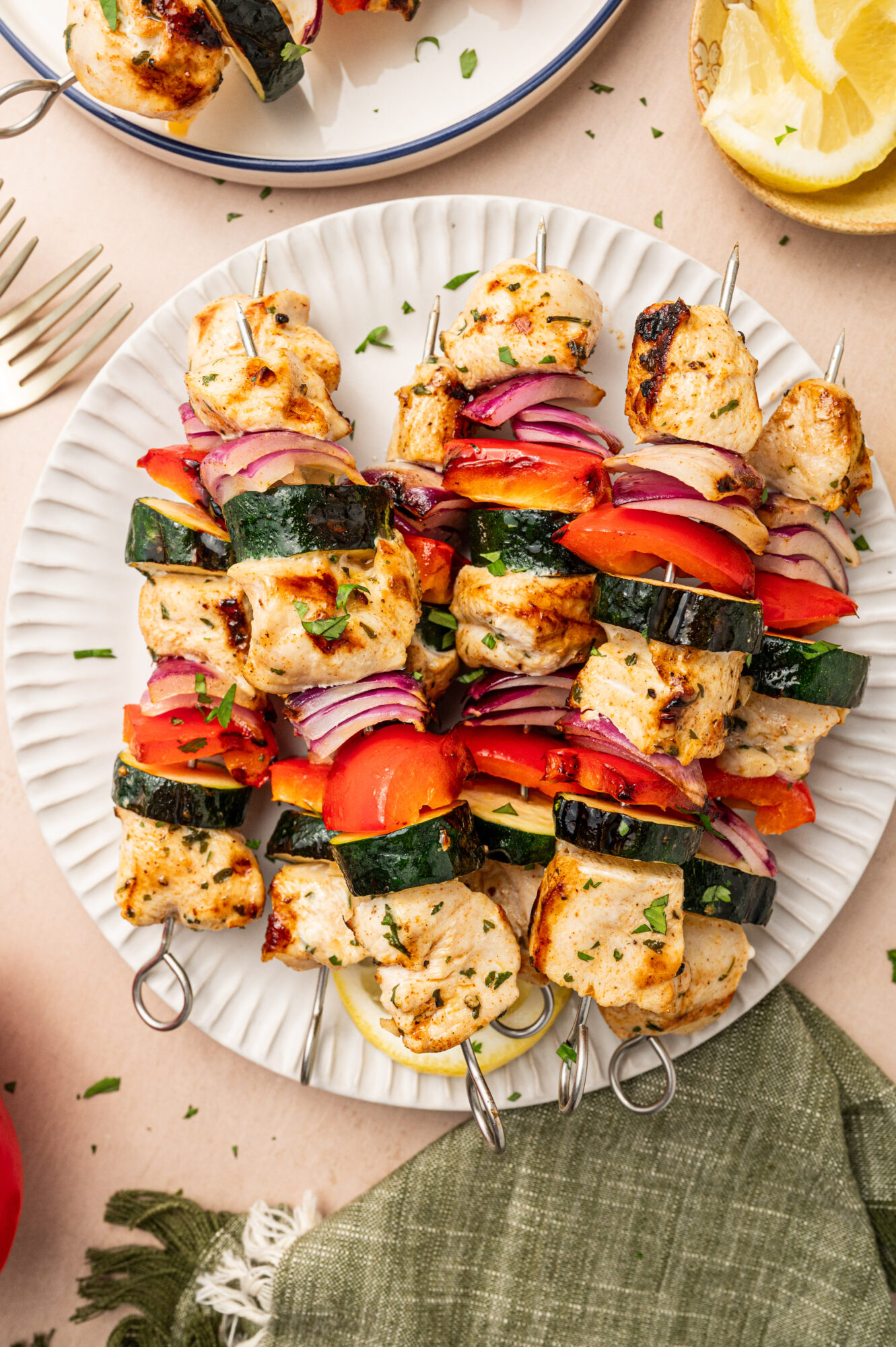 Grilled chicken kabobs on a paper plate with red onion, bell pepper, and zucchini.