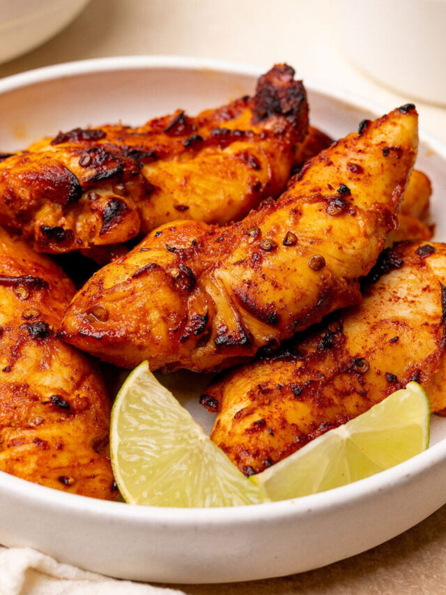 Honey chipotle chicken tenders in a white bowl with lime wedges.