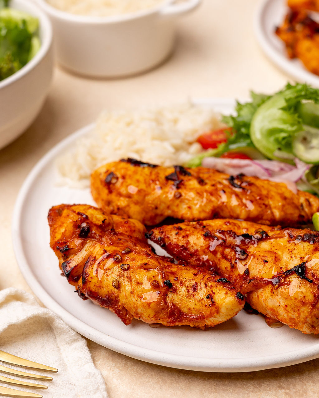 A serving of honey chipotle chicken tenders served with rice and a side salad.