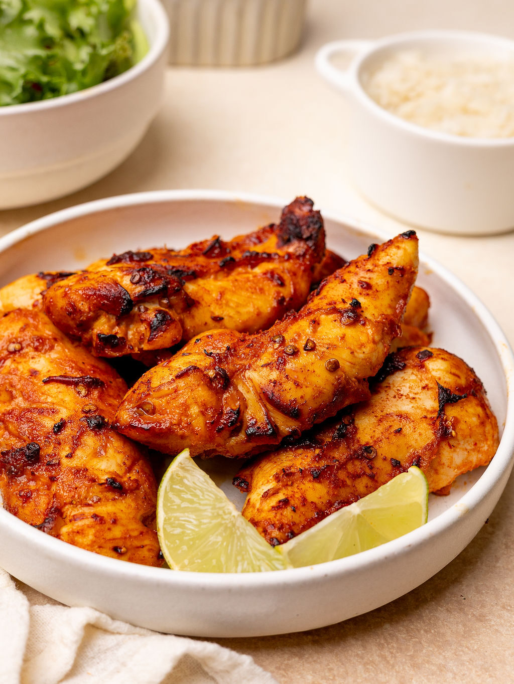 Honey chipotle chicken tenders in a white bowl with lime wedges.