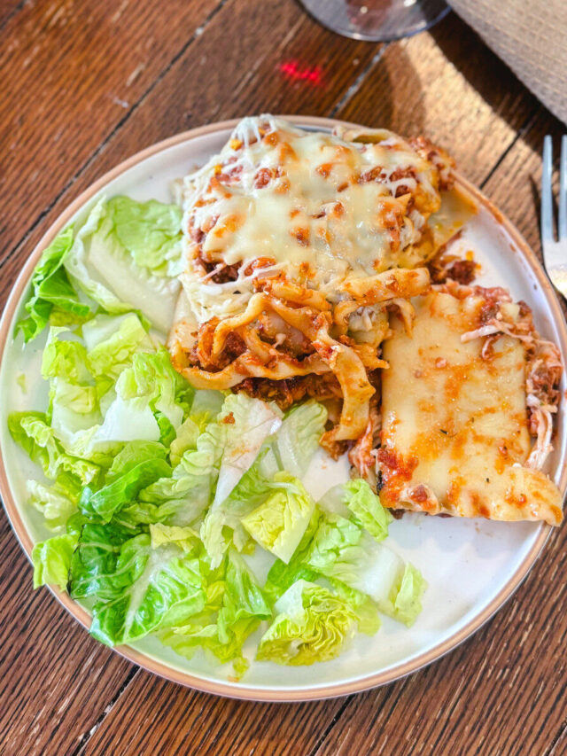 Lasagna Roll-Ups on a plate with a side salad over a wooden table.