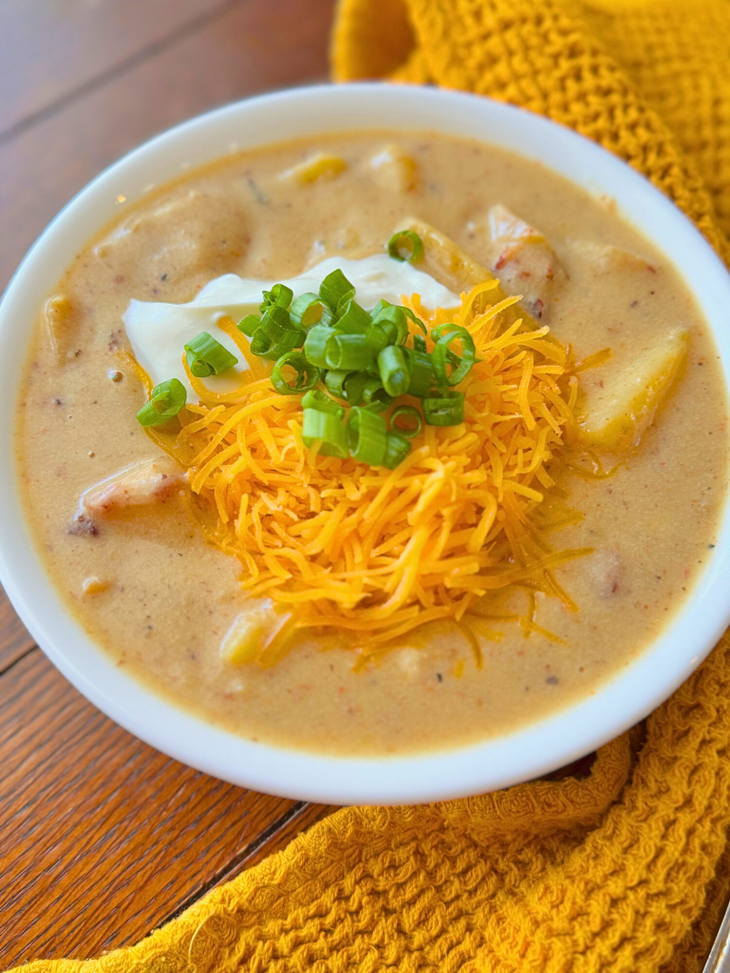 Close-up of loaded potato soup over a rustic wooden surface.